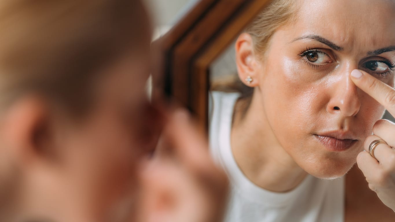 woman picking at nose in mirror